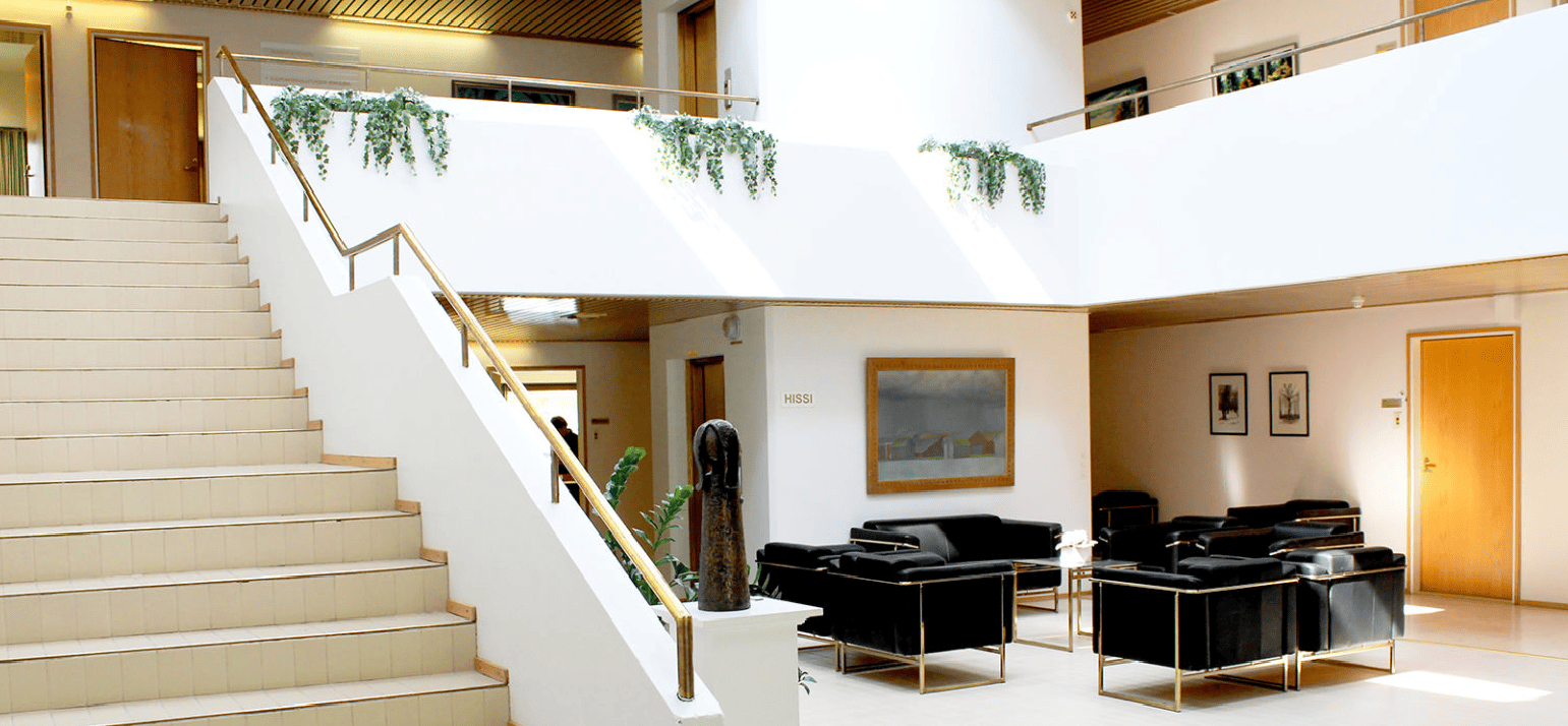 Viraston aula, portaat yläkertaan ja alakerrassa sohvaryhmä